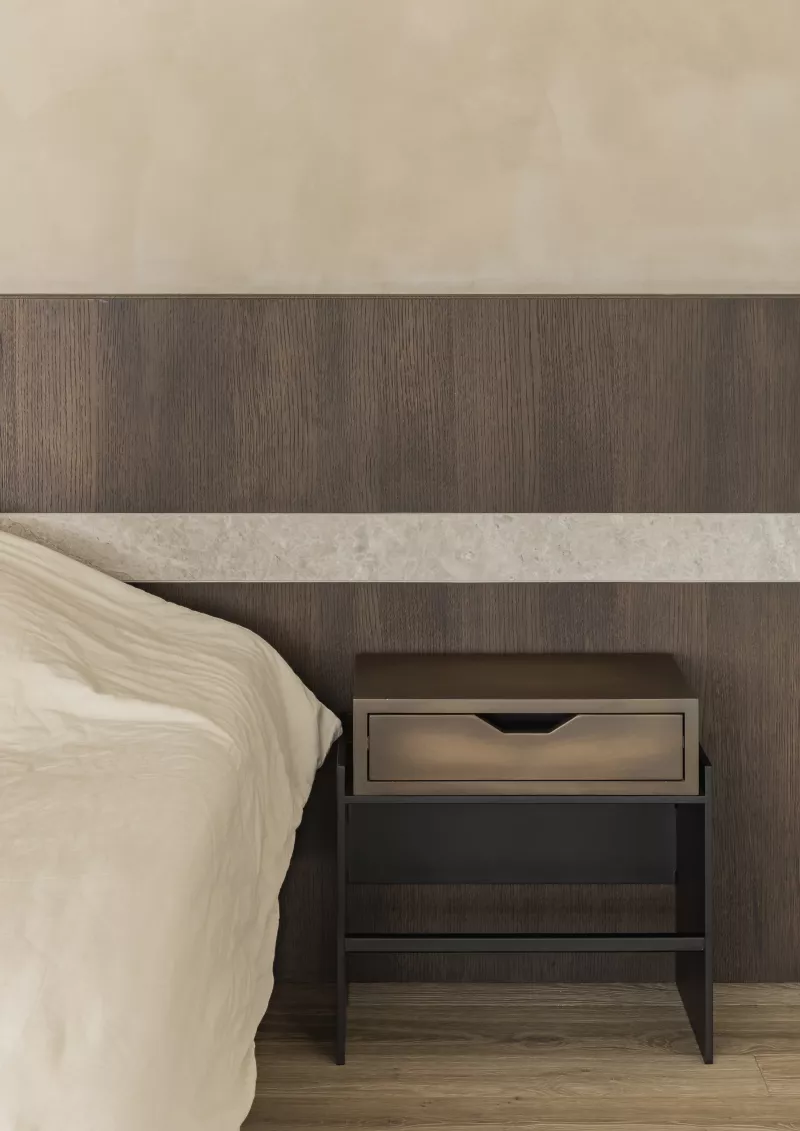 Zicht op bedwand met natuursteen detail en bijzettafel op maat